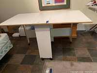 Table fully opened showing white top, central support panels and drop leaves extended