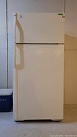 Frontal view of the white Kenmore refrigerator showing top freezer and main fridge compartments with vertical handles.