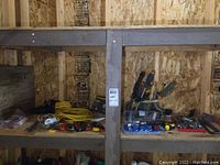 Wide view showing assortment of hand tools on wooden shelves including wire cutters, screwdrivers, and organizing trays.