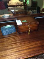 Wooden jewelry box and blue trinket box on polished wooden surface with mirror reflection