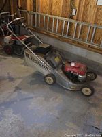 Full side view of mower showing steel deck, engine housing, handlebars and attached grass bag