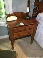 Front angle view of nightstand showing two drawers and turned legs