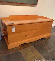 Closed solid pine wood chest showing natural finish, wood grain, and some scratches on top surface.