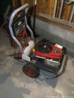 Full side view of the pressure washer showing engine, frame, hose, spray gun and detergent tank