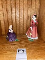 Both figurines placed on a wooden shelf, showing size difference and general condition.