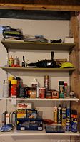 Shelves holding various spray cans and containers including paint, sealers, WD-40, glue bottles, chalk line, and tools.