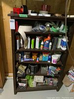 Full view of wood bookcase filled with rolls of tape, bottles, and repair supplies on five shelves.