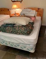 Side view of assembled twin bed showing mattress, box spring and bedding stack (bedding not included).