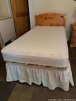 Front view of assembled single bed showing mattress, box spring and pine headboard