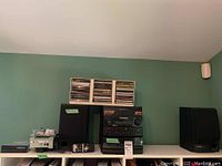 Wide shot showing the entire stereo system, speakers, external hard drive, remote, and CDs on a shelf.