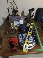 Full view of all items including propane torches, soldering gun, level, sander, electrical wires, safety goggles, and hand tools on table.
