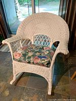Front-right three-quarter view of white wicker rocking chair with cushion