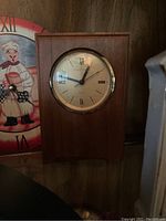 Wooden mantle clock with gold rimmed face and Roman numeral hour markers