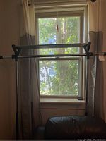 Full view of metal clothing rack in front of window, showing horizontal hanging bar and frame.