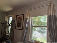View of two sets of curtains hung on windows in a room, showcasing the two-tone cream and silver-gray curtains.