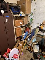 Basement storage with labeled boxes for Valentine, Easter, St Patrick's Day, Halloween, stacked with paper plates and framed artworks visible.