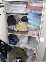 View of folded linens stored on shelves including towels, sheets, blankets in multiple colors