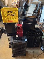 Wide view of stacked yellow, black, and red plastic crates in basement with various background items