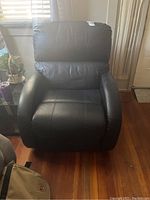 Front view of black leather recliner armchair showing overall condition and size relative to room.