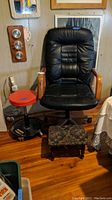 Black wheeled swivel office chair, red pneumatic roller stool, and small floral upholstered footstool together in room corner.