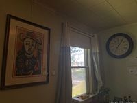 Framed wall art print and round wall clock mounted above window