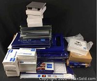 Display of stacked clipboards, check presenters, packaging boxes and bubble-wrapped items forming a collection of branded promotional materials