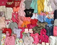 Hundreds of baby girl clothes pieces from 0-18 months, colors include pink, coral, red, white, aqua, yellow, purple with patterns including floral and animal prints shown spread out for overview.