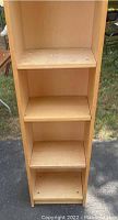 Front view of wooden book shelf showing four shelves and some blemishes on surfaces.