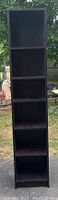 Full view of dark wooden bookcase with five shelves outdoors showing overall condition and structure