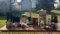 Table display showing assorted collectibles and holiday items including boxed doll, Santa figurine, and Waterford corner hutch pieces