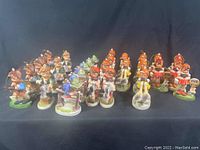 Lot of 28 vintage Hummel style Christmas ornaments with various children and bird figures, arranged in rows on a black background