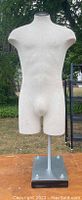 Front view of off-white male mannequin torso on metal base with adjustable pole.