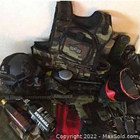 Photo showing tactical vests, helmets, masks, CO2 tanks, harnesses, and various paintball gear arranged together