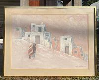 Framed oil painting showing a desert village with adobe buildings, two figures walking wrapped in striped blankets, signed E. Lee lower right.