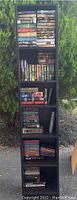 Full view of shelving unit showing multiple rows of vintage paperback and hardcover books tightly packed, outdoor natural background