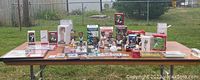 Wide shot of large assortment of sports memorabilia items displayed on table outdoors, including bobbleheads, cards, ornaments, and framed pictures mainly related to Philadelphia sports.
