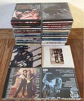 Two stacks of Stevie Ray Vaughan CDs along with four CDs laid out front, showing covers.