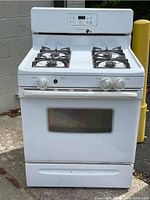 Full view of white Frigidaire gas stove oven with four burners, control panel and oven door showing wear and dirt.