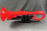 Left side view of the red plastic trumpet showing three black valves and casing.