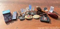 Full view of all lot items including belt buckles, shot glasses, football, pen, and jewelry boxes arranged on a wooden surface