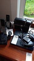 Photo of the lot including VTech cordless phones, Canon camera, Sony Blu-ray player, Tasco binoculars, power adapters, and cases