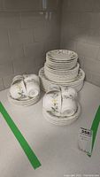 Full set of Mikasa Belle Fleur dinnerware including stacked plates and cups with saucers arranged on countertop