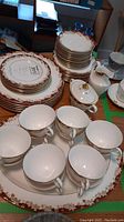 Full view of stacked dinner plates, luncheon and bread plates, cups arranged on a large platter along with sugar bowl and creamer on the right side