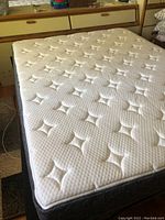 Full view of queen size mattress with white top and patterned surface, placed on adjustable bed base.