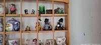 Close view of wooden wall shelf with knick knacks including ceramics, figurines, and glassware