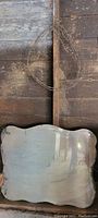 Rustic decorative mirror with scalloped edges and rustic wood backdrop