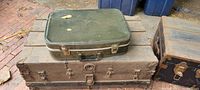 Green vintage hard-sided suitcase on top of medium trunk