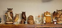 Photo of shelf displaying various owl and hen figurines in multiple materials including ceramic, glass, and wood.