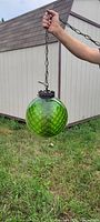 Green textured glass hanging lamp with metal fittings and chain held outside