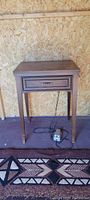 Wooden sewing table with drawer and foot pedal visible on floor.
